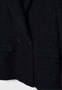 Blazer en laine noire texturée avec deux boutons et poches avant à rabat, mettant en valeur le détail du tissu et les coutures ajustées.