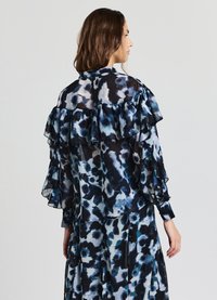 Transparente, geschichtete Bluse in blauem und schwarzem Animal-Print, mit Rüschen-Details an Ärmeln und Rücken, einem knöpfbaren Kragen und manschettenbesetzten Handgelenken.