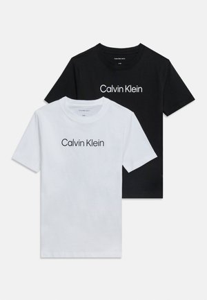 Dwie koszulki z krótkim rękawem i okrągłym dekoltem, jedna czarna i jedna biała, każda z nadrukiem "Calvin Klein" w kontrastowym kolorze na piersi.
