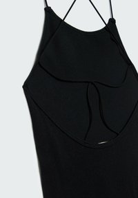 Robe noire sans manches avec fines bretelles et détails découpés décoratifs sur la partie supérieure de la poitrine et la taille, sur un fond uni.