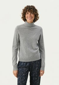 Grauer Rollkragenpullover mit langen Ärmeln, aus weichem Material, mit gerippten Bündchen und Saum, kombiniert mit gemusterten, dunklen Hosen.