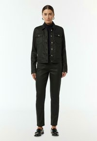 Czarna dżinsowa kurtka z przednimi kieszeniami i srebrnymi guzikami, w zestawie ze slim fit czarnymi spodniami z sztucznej skóry i czarnymi mokasynami. Gładka faktura.