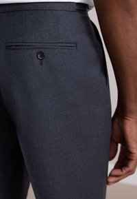 Dark gray tailored trousers with a smooth texture. Features a back pocket with a black button and a neat, structured design.