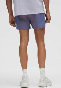 Herrarnas träningsshorts, lila gradientdesign, lättviktsmaterial, elastisk midja, enfärgade vita strumpor, vita sneakers med diskret logotyp.