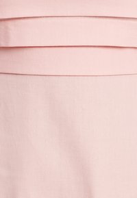 Vaaleanpunainen kangas, jossa on sileä pinta, ja vaakasuorat laskokset ylhäällä, luoden kerroksellista suunnittelua.