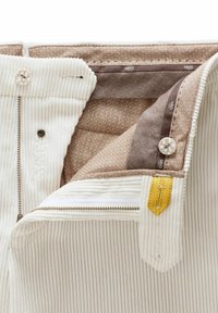 Weiße Cord-Hosen mit einem kontrastierenden braunen Innenfutter und einem goldenen Akzent am Reißverschluss. Verfügt über einen Knopf und detaillierte Nähte.