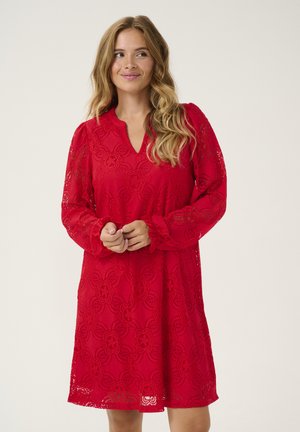 Röd spetsklänning med långa ärmar, V-halsringning, blommönster och en avslappnad passform som når till mitten av låret. Den texturerade tyget tillför djup.