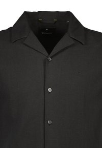 Zwarte blouse met kraag, gemaakt van een gestructureerde stof, met een knoopsluiting aan de voorkant, een subtiele merklogo en contrasterende stiksels.