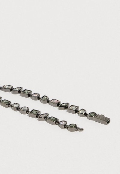 Mustast metallist käevõru, millel on vahelduvad rohelised ja läbipaistvad mitme kujuga vääriskivid, ristkülikukujuline pannal, millele on graveeritud brändi nimi.