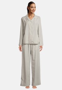 Ljusgrå satinpajamaset med knapp-up topp och krage samt löst sittande byxor. Slät textur, avslappnad design.