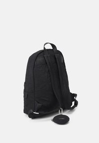 Czarny pikowany plecak z regulowanymi paskami, boczną kieszenią i okrągłą przymocowaną saszetką. Teksturowana powierzchnia o geometrycznych wzorach.
