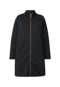 Abrigo negro con cremallera y cuello alto, que presenta un sutil patrón embossado, bolsillos laterales y un detalle de cremallera dorada. Tejido suave y texturizado.