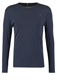 Ciemnoniebieska koszulka z długim rękawem i okrągłym dekoltem z małym logo na górnej lewej części klatki piersiowej oraz gładką teksturą materiału.