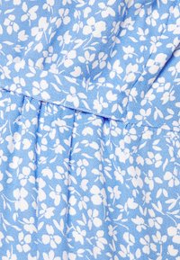 Tecido azul com um padrão floral em branco, apresentando pequenas flores e folhas. A textura parece suave com um ligeiro brilho.