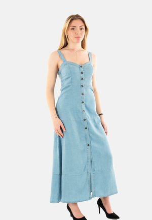 Abito lungo in denim azzurro chiaro con corpetto aderente, scollatura quadrata, chiusura con bottoni sul davanti e spalline regolabili; abbinato a uno spacco e tacchi neri.