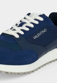 Μπλε και ναυτικό αθλητικό παπούτσι με λευκά κορδόνια, υφή στη σόλα και λογότυπο "VALENTINO" στο πλαϊνό πάνελ.