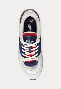 Sneakers med marinblå och vit textilöverdel med röda accenter, runda skosnören och en logotagg. Texturerade meshpaneler förbättrar andningsförmågan.