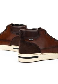 Bruine leren high-top sportschoenen met suede accenten, ronde veters, een crèmekleurige rubberen zool en een klein logo nabij de hak.