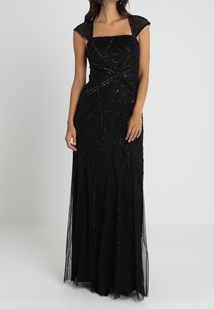 Femme portant une robe de soirée noire longue jusqu'au sol avec des manches courtes et des détails complexes en perles.