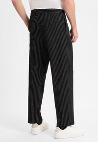 Zwarte pinstripe broek van stof met een gladde textuur, met achterzakken en een recht model, gecombineerd met witte sneakers.