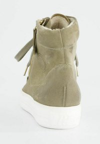 Bottine en daim vert olive avec semelle en caoutchouc blanche, fermeture à glissière et détails en lacets, doublure intérieure douce et logo embossé à l'arrière.