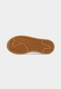 Semelle de chaussure en caoutchouc brun avec des motifs en zigzag et des lignes de contour sur un fond clair uni.