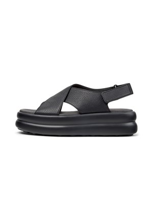 Black leather sandals with cross-strap design, open toe, and padded black platform sole. Features adjustable strap at the back.