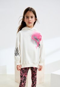 White hooded sweatshirt with pink graffiti patterns and black accents. Paired with black leggings featuring a pink abstract design.