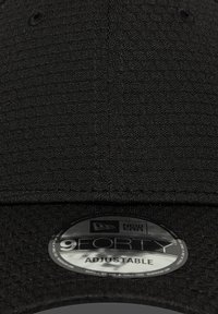 Cască neagră, ajustată, cu un material texturat, vizor curbat și un eticheta circulară care afișează "9FORTY ADJUSTABLE" împreună cu logo-ul brandului.