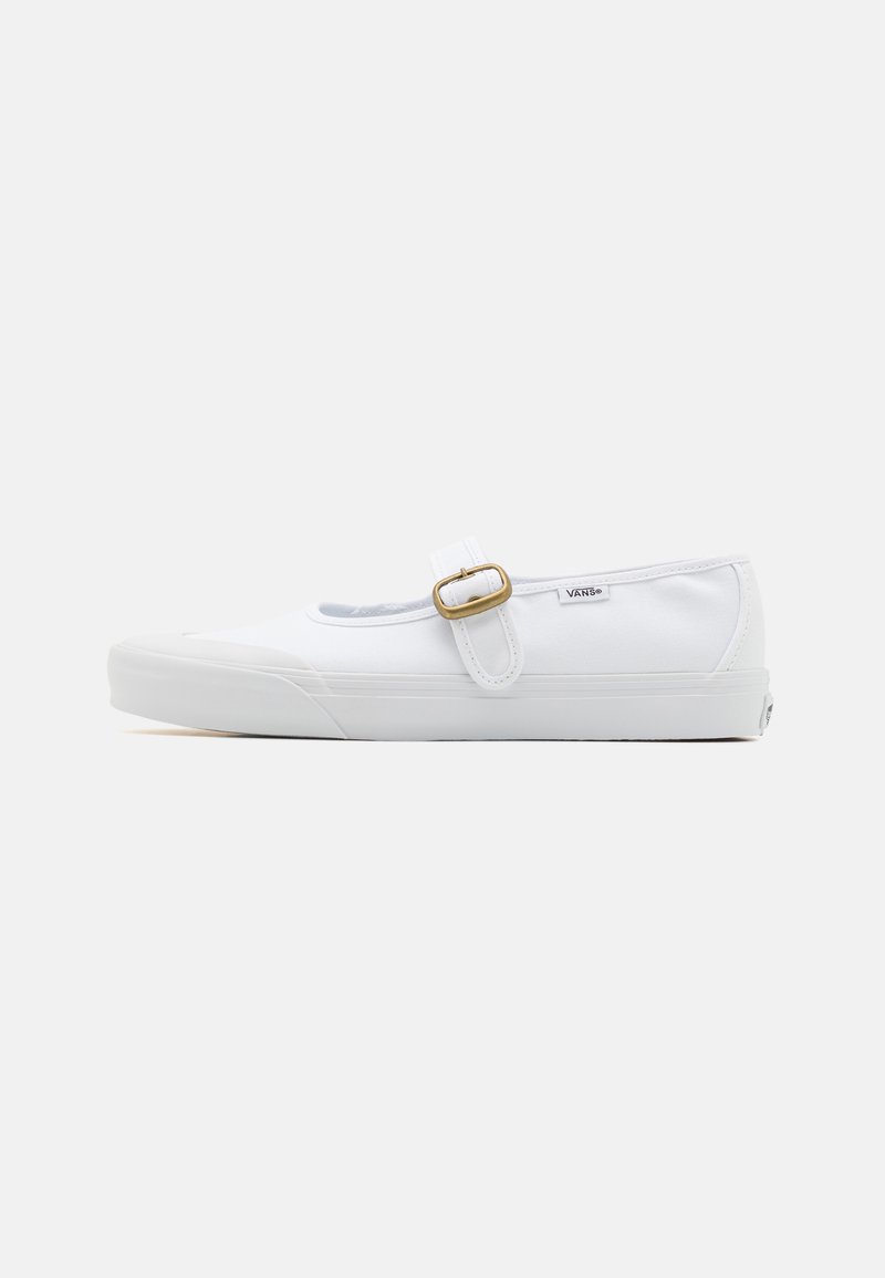 Zapatilla de lona blanca tipo slip-on con punta redonda, suela de goma y detalle de correa con hebilla en el lateral. Presenta costuras mínimas y una marca de logo.