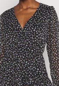 Schwarzes Kleid mit einem floralen Muster in Lavendel und Pink, mit einem tiefen V-Ausschnitt und langen transparenten Puffärmeln, gerafftem Taillenbereich und gestuftem Saum.