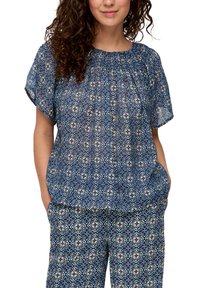 Blauwe gebloemde blouse met korte mouwen en een geplooide halslijn. Heeft een geometrisch bloemontwerp in lichte en donkere blauwtinten.