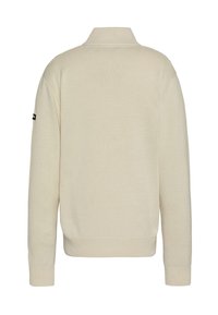 Kremowy sweter z wysokim kołnierzem, prążkowaną fakturą, długimi rękawami i czarną naszywką z logo na lewym rękawie. Minimalistyczny design.