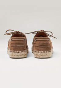 Espadrilles en suede marron avec un design à lacets, présentant une semelle en jute et des détails sur les côtés. Fini texturé avec des coutures contrastées.