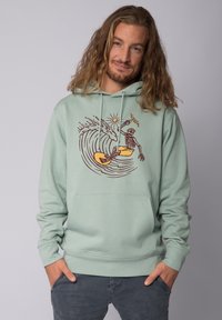 Muntgroene hoodie met een frontgraphic van een skelet dat op een golf surft, met een zon en handgetekende details in bruin en geel.