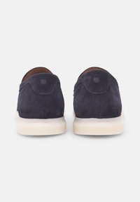 Marineblaue Wildleder Slipper mit einer kontrastierenden cremefarbenen Gummisohle. Minimalistisches Design mit Nähakzenten und einem kleinen Logodetail an der Ferse.