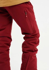 Rode skibroek gemaakt van waterdicht materiaal met een slim fit, contrasterende ritszak en taps toelopende pijpen voor gemakkelijke beweging en comfort.