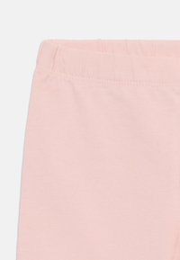 Light pink cotton leggings with an elastic waistband, featuring a smooth texture and simple design without patterns or embellishments.