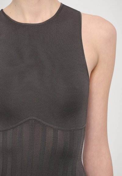 Dark gray fitted top with ribbed texture, high neckline, and sleeveless design. Features a contoured, wavy hem and vertical stripes at the base.