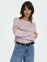 Lichtroze langemouwen top met een relaxed fit, gecombineerd met high-waisted blauwe jeans en een zwarte riem. Zachte textuur, minimalistisch ontwerp.