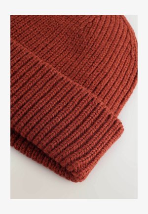 Gestrickte Mütze in tiefem Rostrot, mit geribbelter Textur und umgeschlagenem Saumdesign. Gefertigt aus einem dicken, warmen Garn.