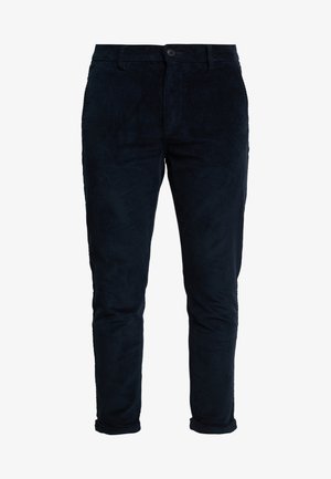Granatowe spodnie dżinsowe z prążkowanej tkaniny, o dopasowanym kroju, z kieszeniami z przodu i zapięciem na guzik. Teksturowana tkanina z pionowymi prążkami i podwiniętymi mankietami.