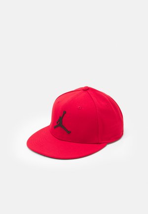 Cappello da baseball rosso in cotone con visiera piatta, dotato di un logo Jumpman nero sul davanti e fori di ventilazione sui lati.