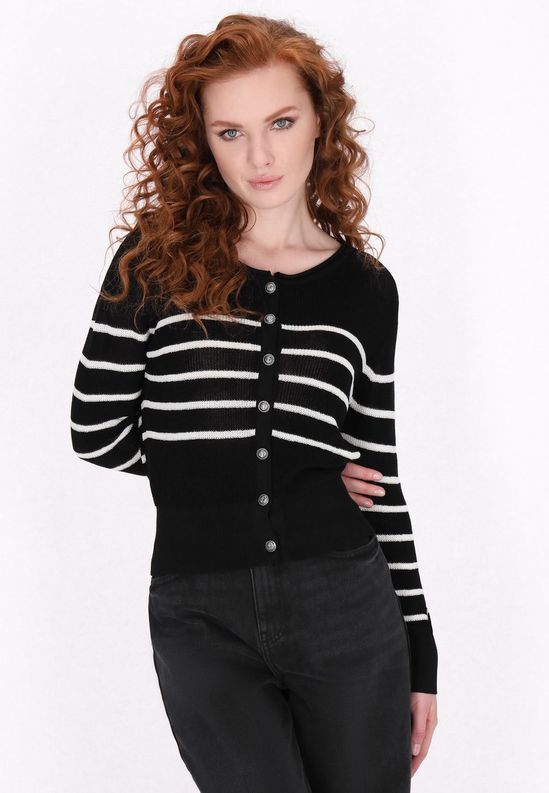Cardigan a righe bianche e nere con collo rotondo, chiusura con bottoni, maniche lunghe e orlo a coste. Il tessuto sembra lavorato a maglia con una texture liscia.