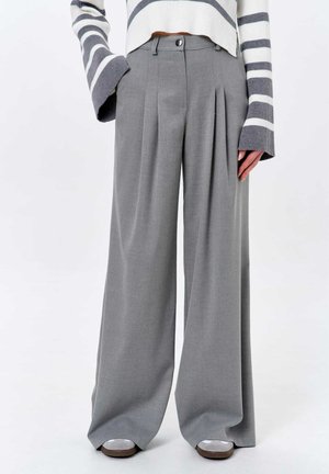 Pantalons larges gris avec plis, fabriqués à partir d'un tissu lisse. Dotés d'une fermeture à bouton et se portant taille haute, alliant fonctionnalité et style.