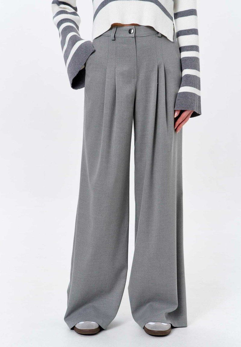 Graue weite Hosen mit Falten, gefertigt aus einem glatten Stoff. Verfügt über einen Knopfverschluss und sitzt hoch in der Taille, verbindet Funktionalität mit Form.