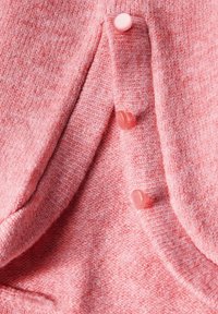Rosa stickad tyg med ett texturerat mönster och tre matchande knappar längs sömmen. Mjuk, varm känsla med en subtil gradient.