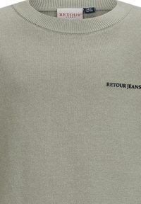 Hellgrüner Strickpullover mit ribbeligem Rundhalsausschnitt und schwarzem "RETOUR JEANS"-Logo. Weicher Stoff, lässiges Design und normale Passform.
