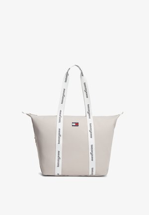 Borsa a mano beige con coulisse logo bianco, caratterizzata da una texture liscia, chiusura con cerniera superiore e una piccola toppa logo Tommy Jeans sul davanti.