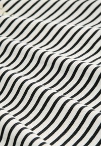 Tissu en coton avec des rayures ondulées noires et blanches. Texture douce, motifs espacés uniformément et légère brillance qui ajoutent de l'intérêt visuel.